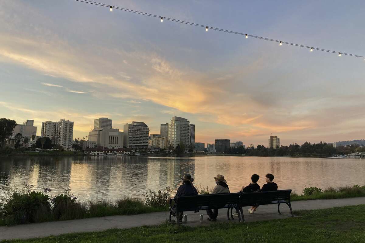 A group sits at a bench along a path at Lake Merritt in Oakland, Calif., Saturday, Nov. 27, 2021.