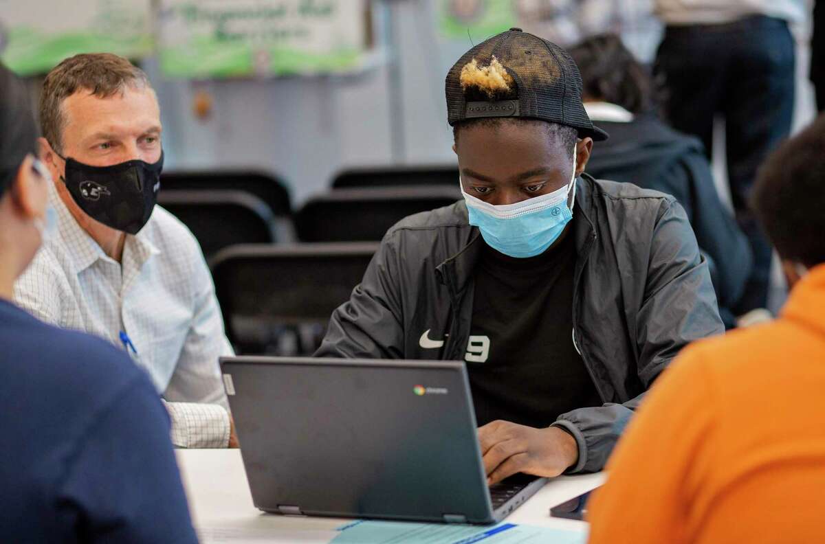 AISD counselor Jeff Healey (left) watches as Penueli Kihundu, 19, (right) applies for the FAFSA during the FAFSA fair workshop at Eastside Early College High School on December 11, 2021 in Austin, Texas.