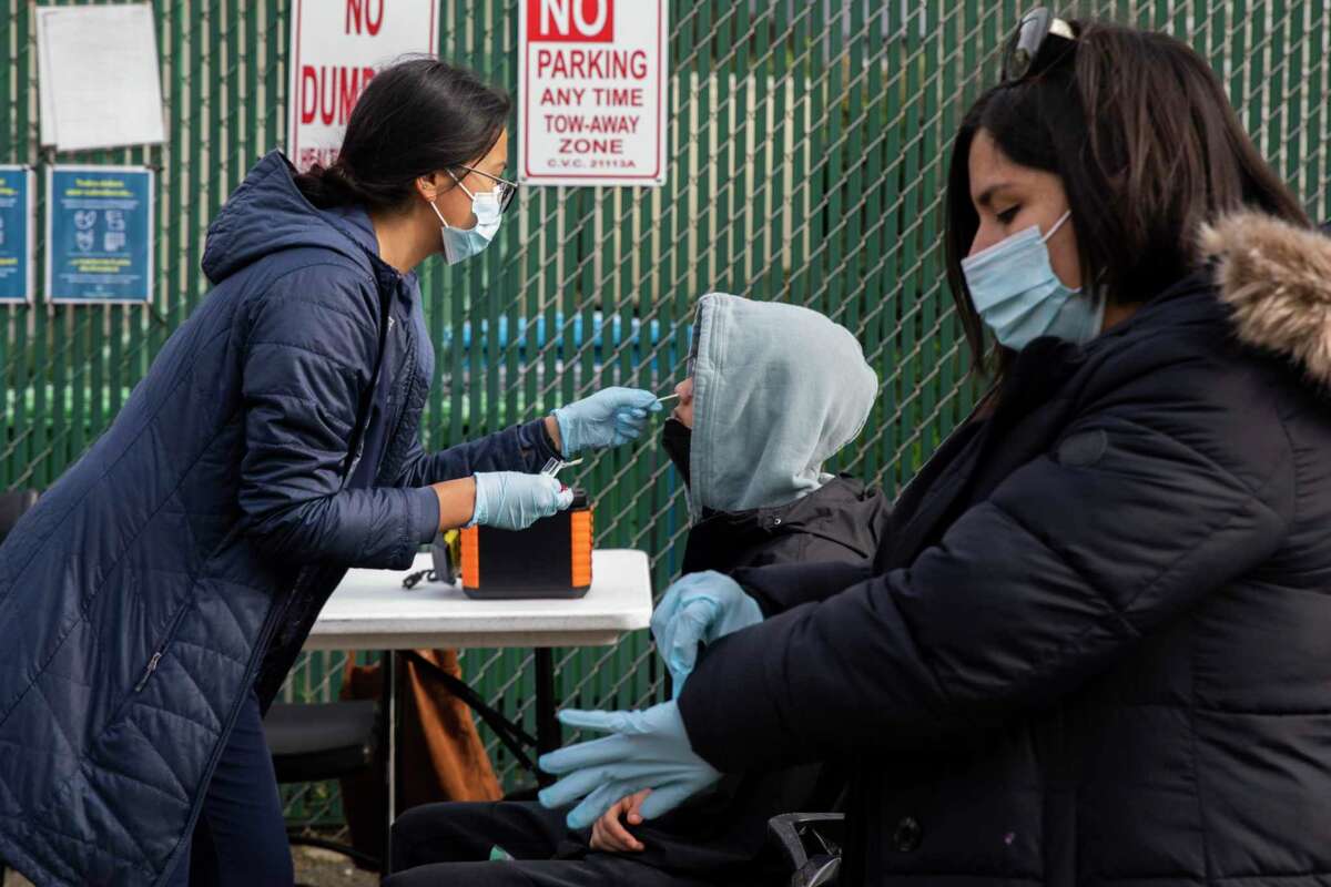 Alyssa Amante (left) administers a COVID-19 test to a student in S.F., Monday, Jan. 3. The Bay Area is averaging 9,700 cases a day over the holiday weekend.