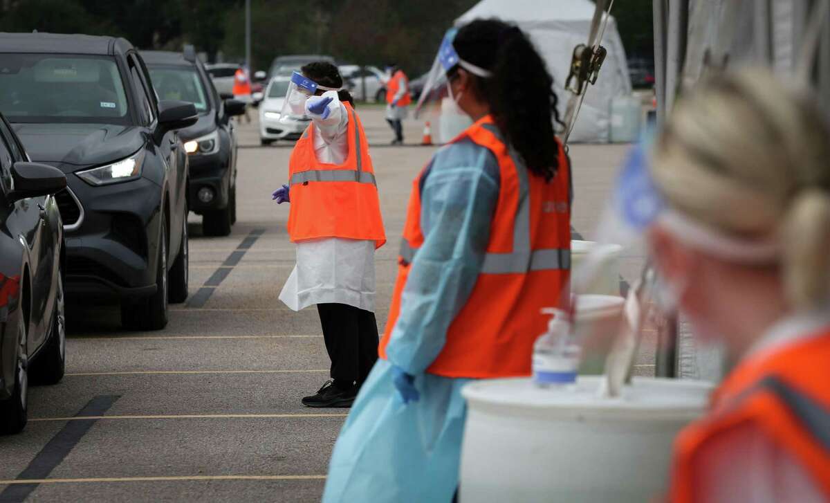 Luisa Hernandez helps people administer a self-administer a COVID-19 test Wednesday, Dec. 29, 2021, at Delmar Stadium in Houston. The Houston Health Department and Curative opened the drive-thru mega-site that morning.