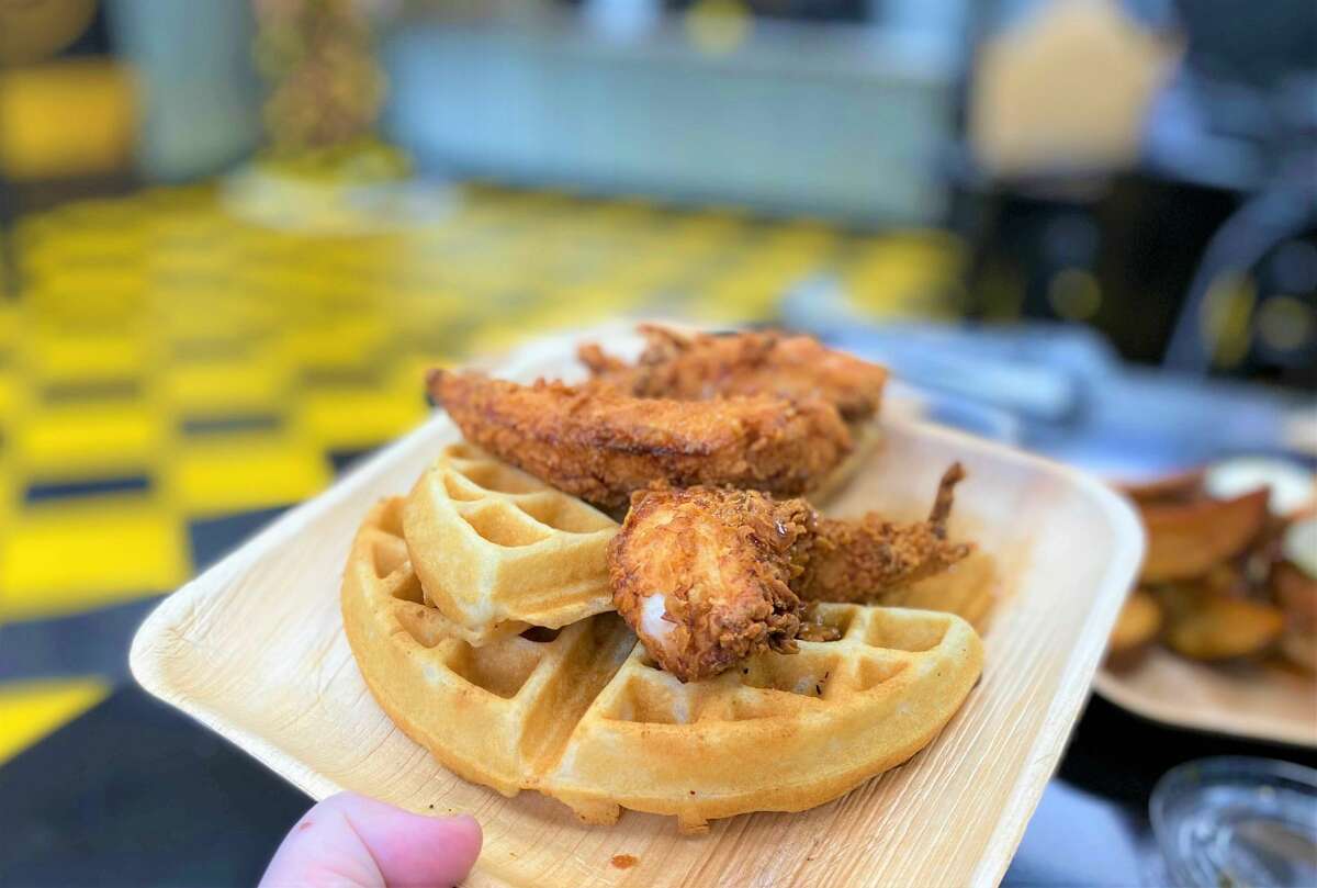 An order of chicken and waffles at Craftbird, with two fried tenders and maple syrup.