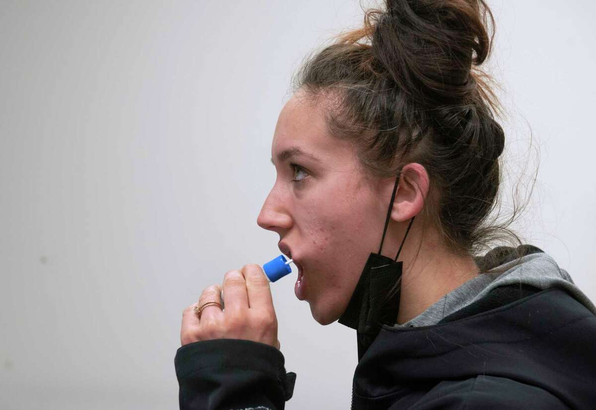 Samantha Reimers of Schenectady swabs the inside of her mouth as she gets tested for COVID-19 at the Schenectady County community COVID testing site on Tuesday, Jan. 4, 2022 in Schenectady, N.Y.