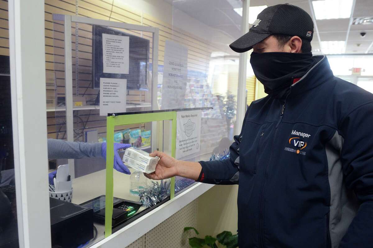 Ever Gonzalez, of Stamford, picks up COVIC-19 home test kits at one of the Hancock Pharmacy locations in Bridgeport, Conn. Jan. 4, 2022.