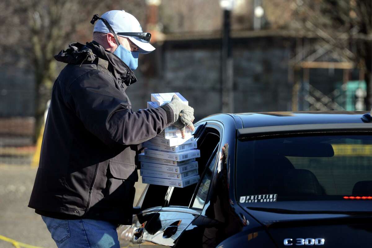 Scott Appleby, Director of Emergency Management, hands out COVID-19 home test kits and protective masks during a drive-thru distribution in a parking lot near Webster Bank Arena and Hartford Healthcare Amphitheater, in Bridgeport, Conn. Jan. 4, 2022.