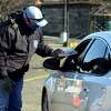 Scott Appleby, Director of Emergency Management, hands out COVID-19 home test kits and protective masks during a drive-thru distribution in a parking lot near Webster Bank Arena and Hartford Healthcare Amphitheater, in Bridgeport, Conn. Jan. 4, 2022.