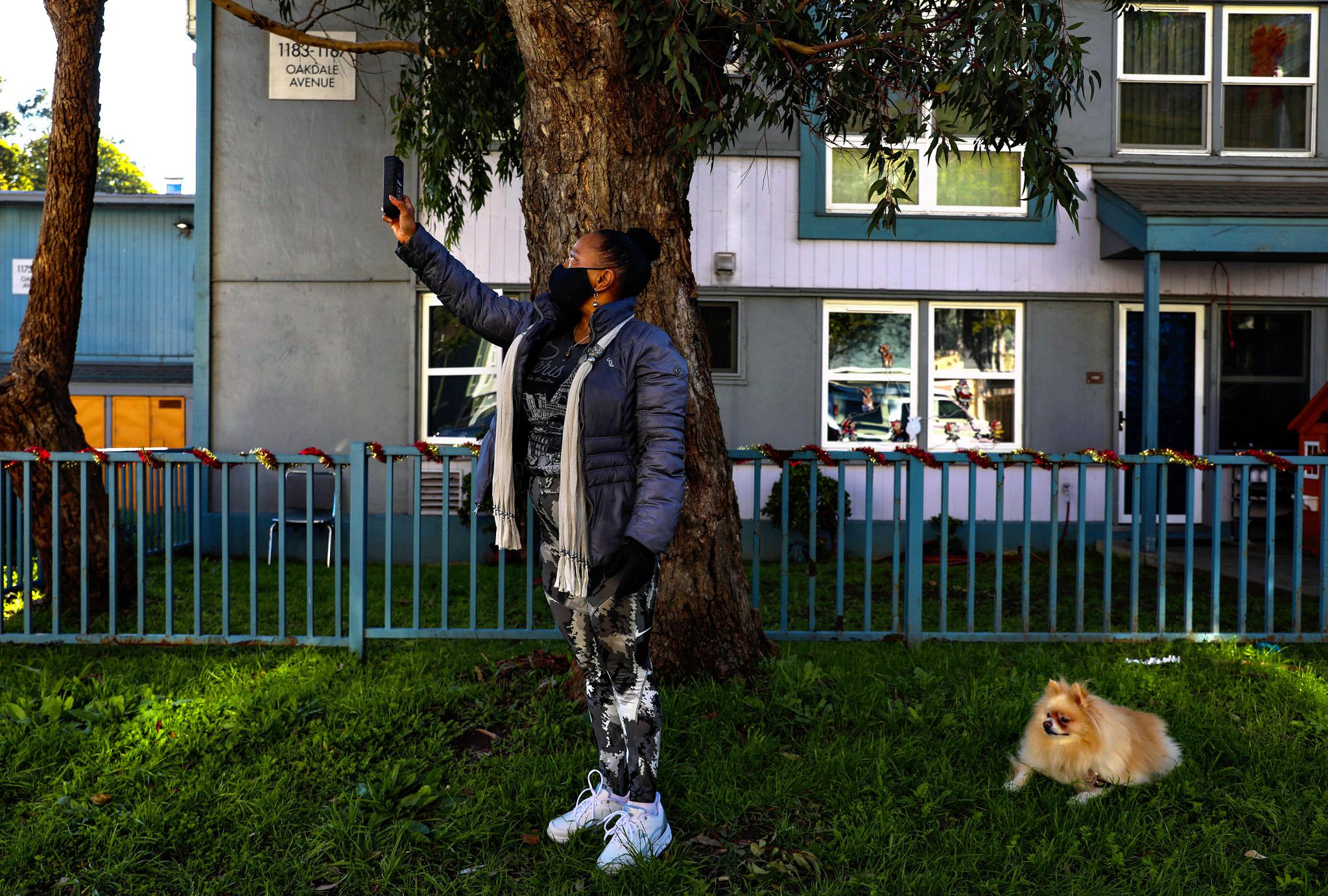 As her Pomeranian, Romeo, rests nearby, Dr. Ahimsa Porter Sumchai conducts a Geiger test outside an apartment building on Oakdale Avenue in San Franci