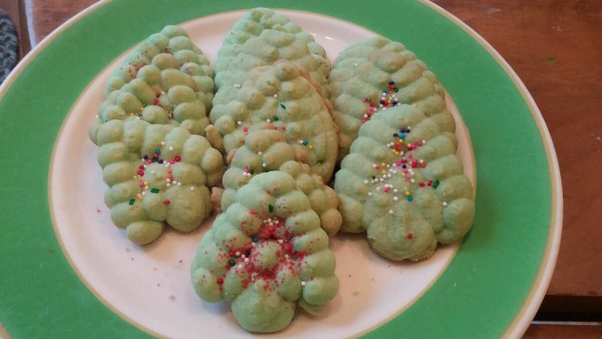 Balsam-green Christmas trees are squeezed from a cookie press and sprinkled with red and green sugar.