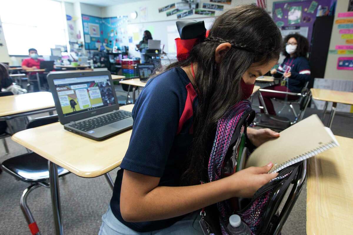Seventh grader Jasmin Resendez grabs her notebook in Cheryl Childs' classroom at Aguirre Junior High in Channelview ISD Tuesday, Oct. 27, 2020 in Channelview. The district has put its mask requirement back in place as students return for the 2022 spring semester due to the recent increase in COVID cases.