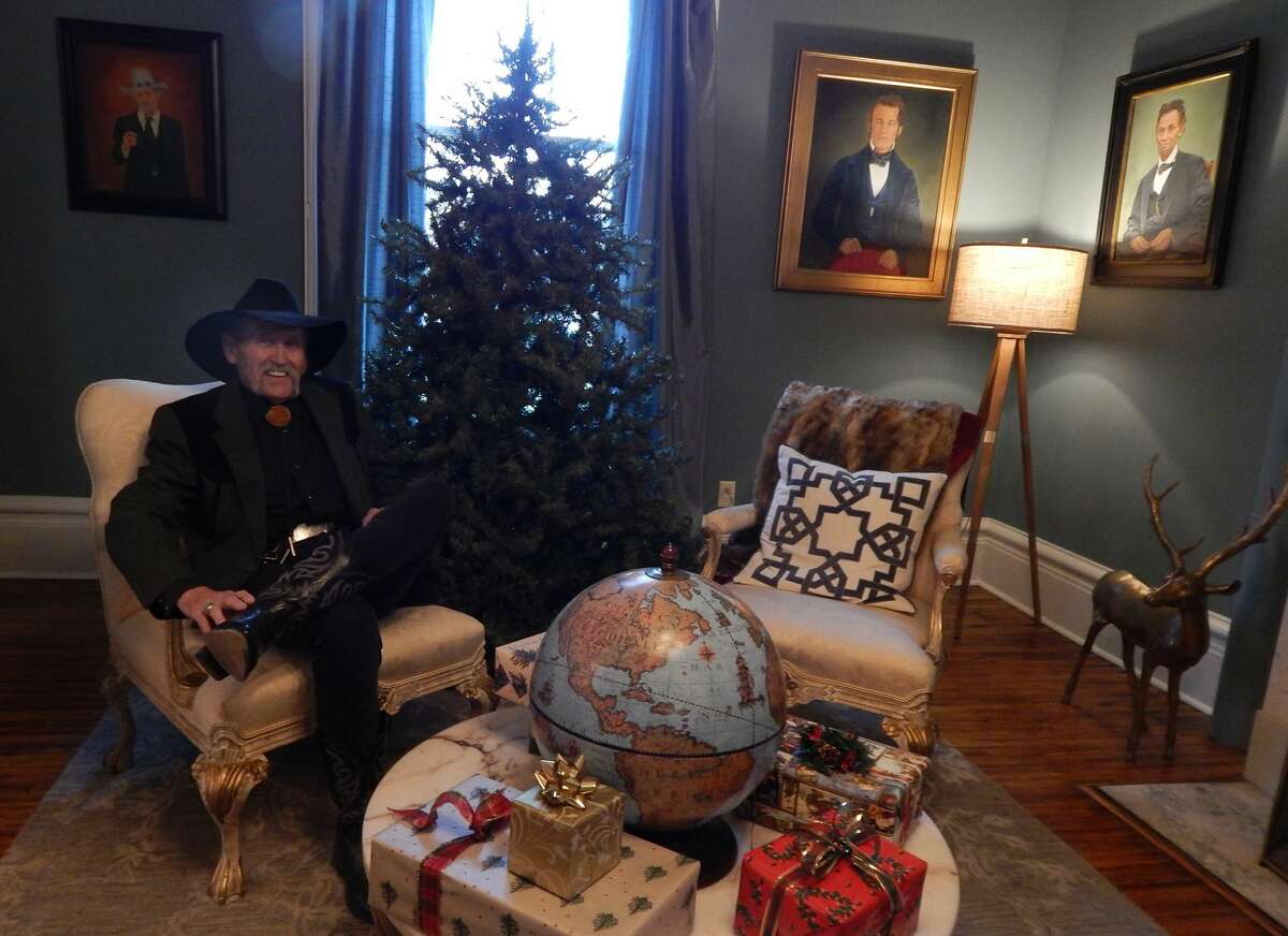 Scotty DeWolf sits just before Christmas in the west parlor of the renovated Ayers Mansion, which he is preparing to open as DeWolf Bed & Breakfast. The portraits behind him to the right, one of Augustus E. Ayers and one of Abraham Lincoln, were painted by Ron Keas, a California-based artist who also painted for DeWolf two other portraits that have gone missing.