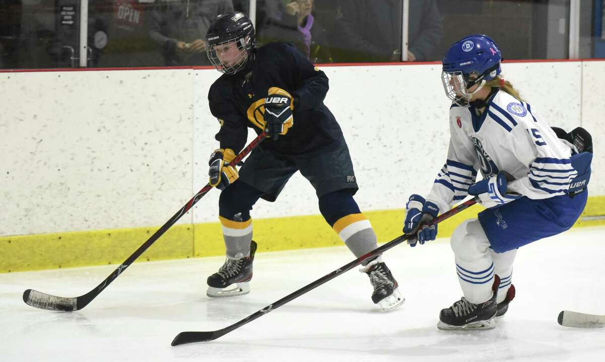 Simsbury's Mackenzie Chapman (3) passes the puck from behind the net while Darien's Lucie Edwards (15) defends during a girls ice hockey game at the Darien Ice House on Tuesday, Jan. 28, 2020.