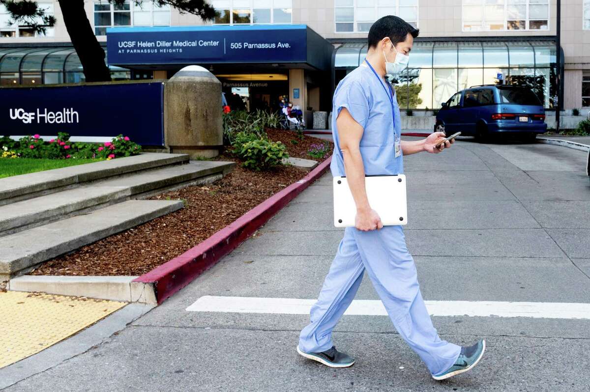 Dr. Peter Chin-Hong checks his phone while walking outside UCSF Medical Center in 2020, in San Francisco.