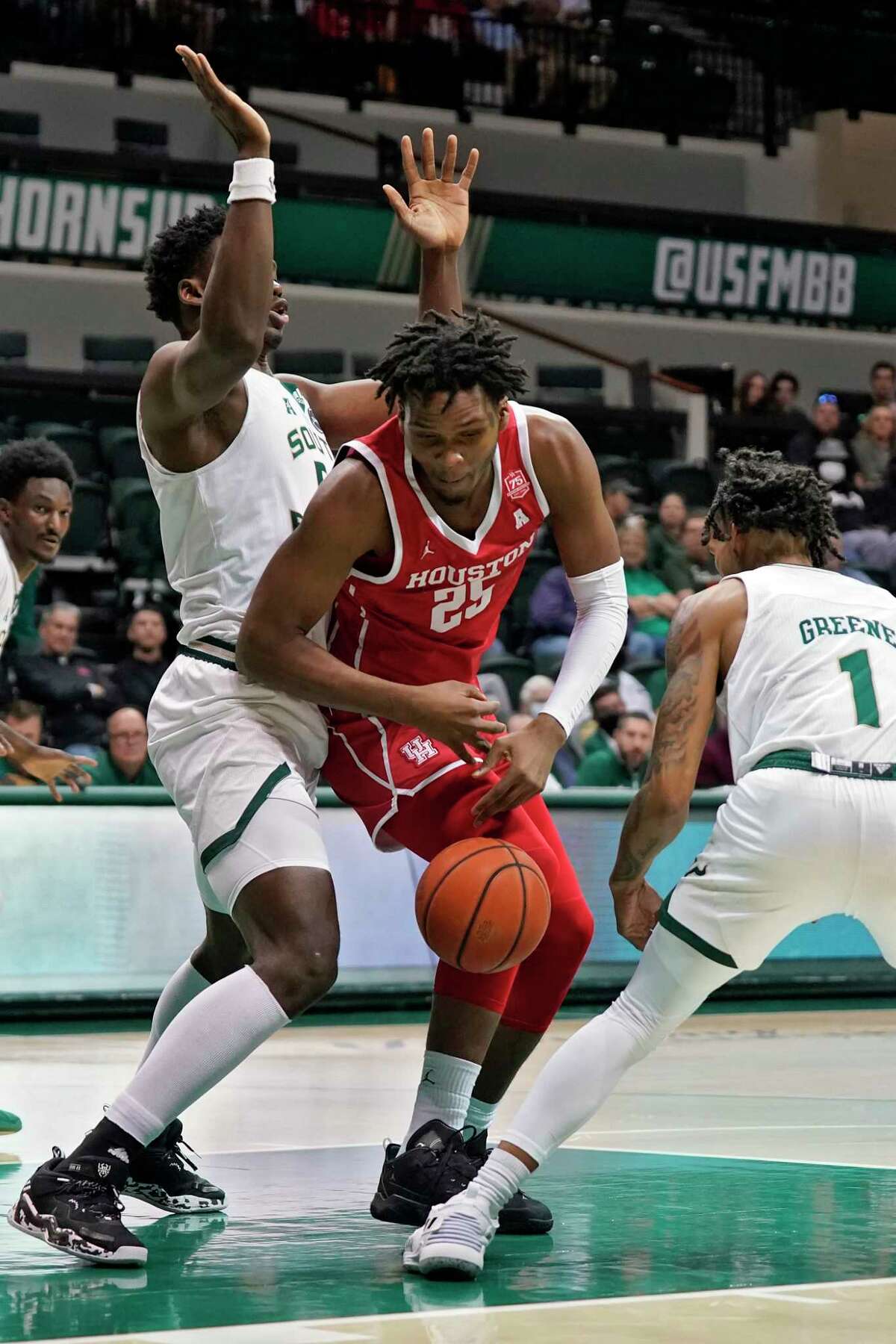Houston center Josh Carlton (25) loses the ball while being stopped by South Florida center Russel Tchewa (54) and guard Javon Greene (1) during the first half of an NCAA college basketball game Wednesday, Jan. 5, 2022, in Tampa, Fla. (AP Photo/Chris O'Meara)