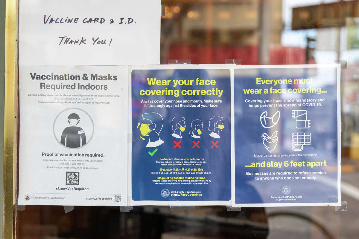 Signs in a business window along Union Street remind customers to wear face masks while indoor their store in San Francisco, Calif. on Jan. 4, 2022.