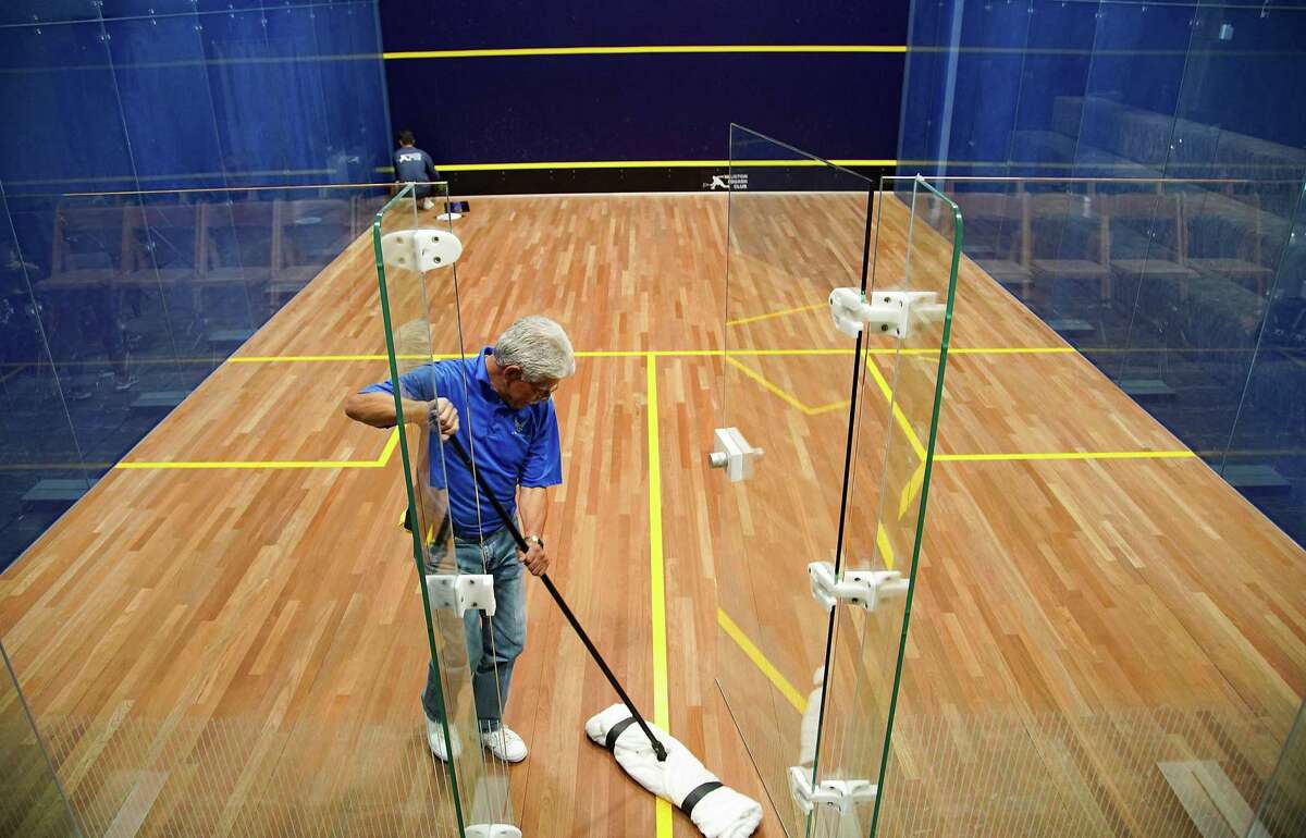 Richard Chavez cleans the squash court at Houston Squash Club before day two of the PSA tournament on Wednesday, Jan. 5, 2022. The tournament has a $110k purse, one of the largest prize money tournaments in the U.S.