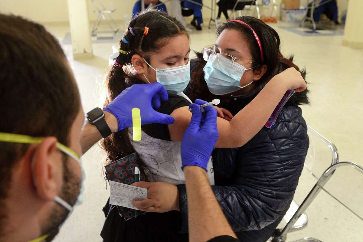 Neriah Saca, 8, of Bridgeport holds onto to her mother, Cristine, as she receives a COVID-19 vaccination during a pediatric vaccine clinic at St. Raphael Academy, in Bridgeport, Conn. Jan. 6, 2022.