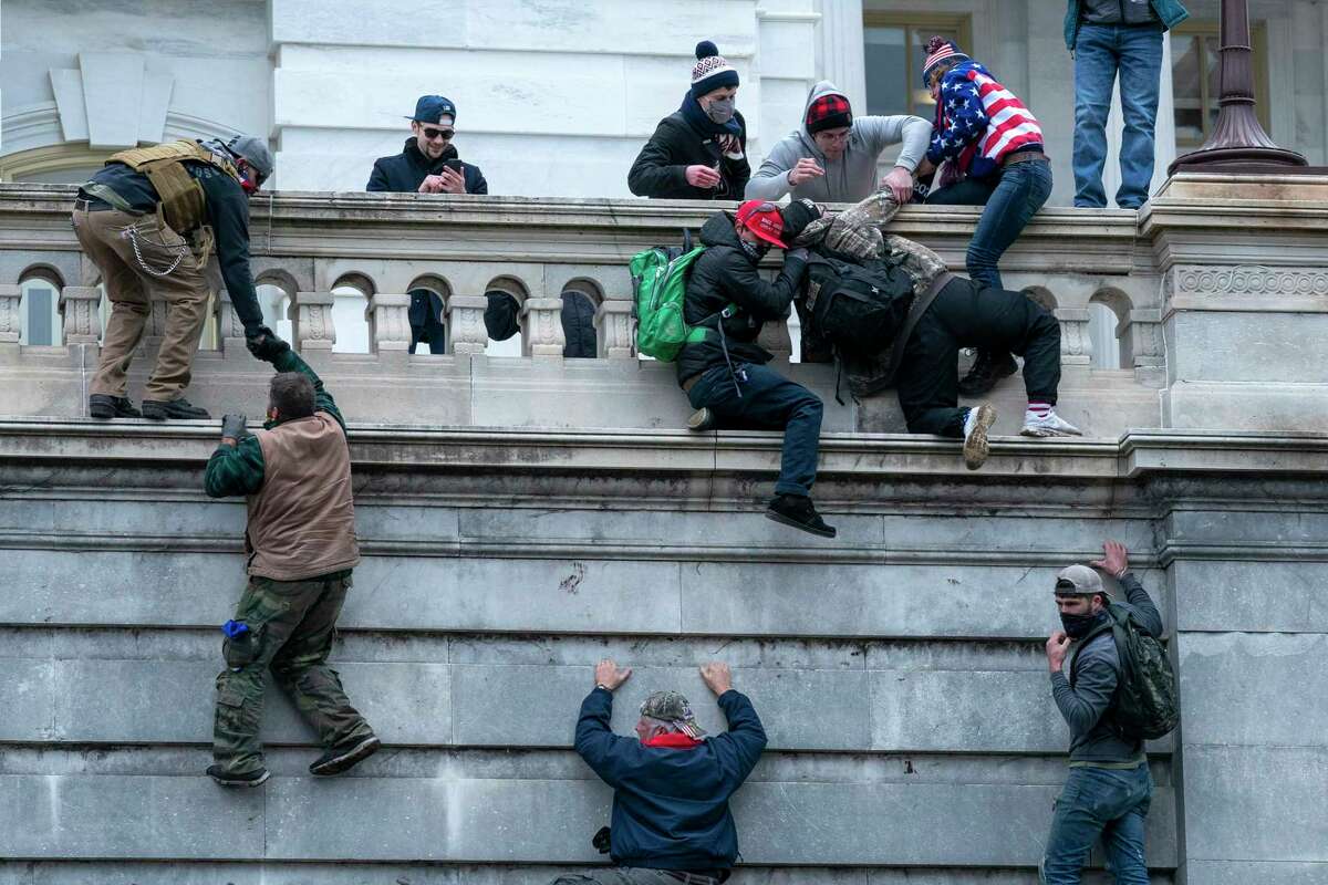 Insurrections loyal to President Donald Trump climb the west wall of the the U.S. Capitol, Jan. 6, 2021, in Washington. 