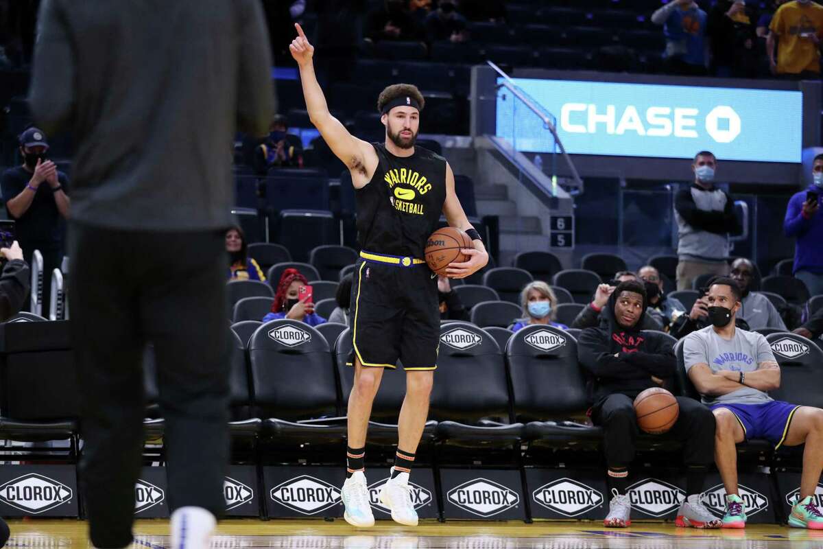 Golden State Warriors' Klay Thompson starts his pregame routine as Miami Heat's Kyle Lowry looks on before NBA game at Chase Center in San Francisco, Calif., on Monday, January 3, 2022.