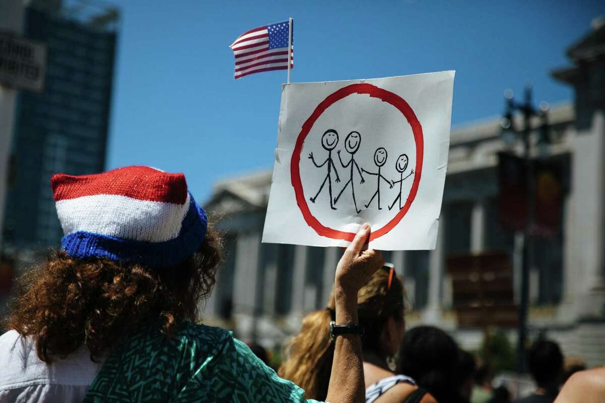 A women holds up a sign during the Families Belong Together rally in front of San Francisco City Hall on June 30, 2018.