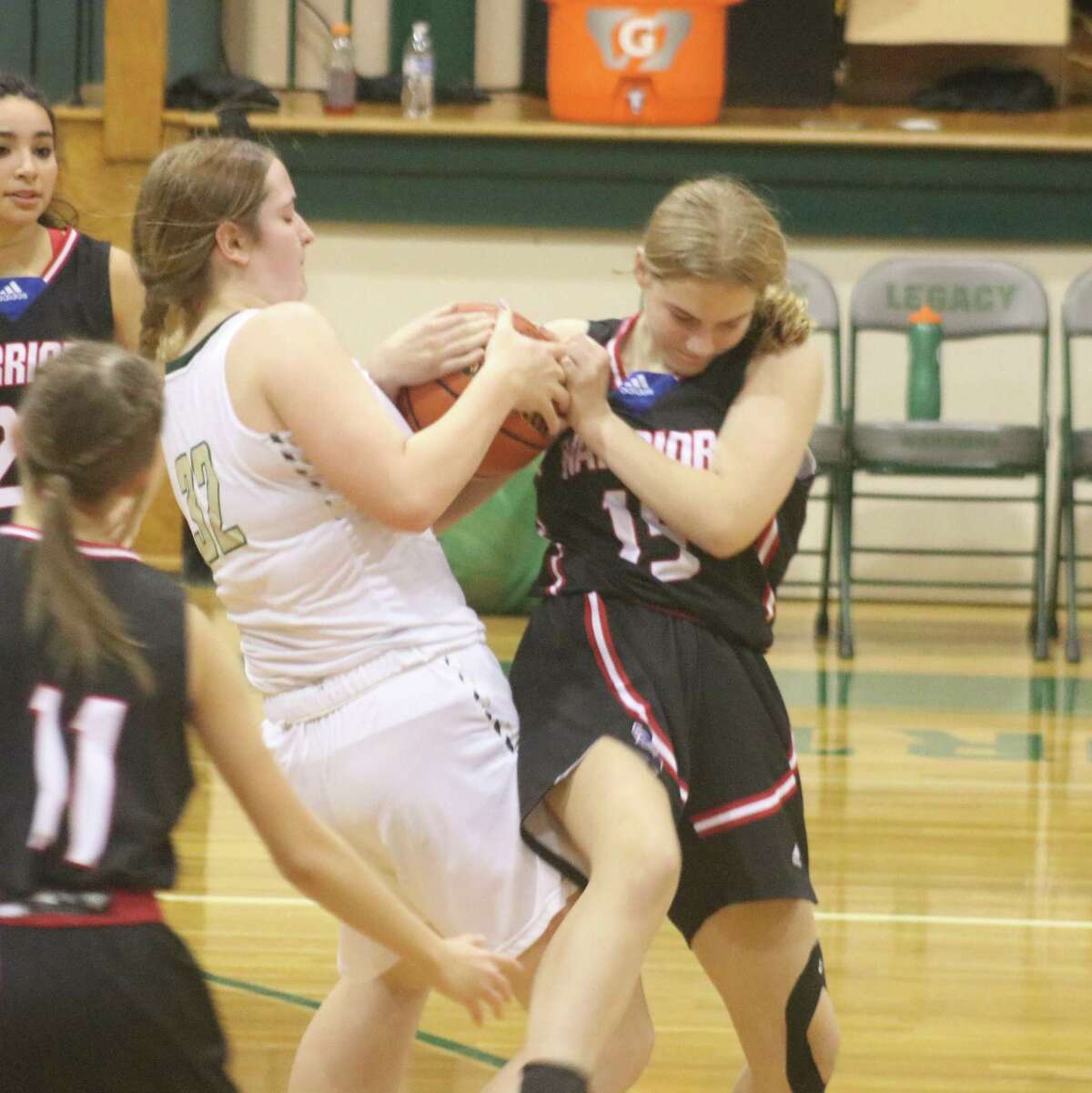 Pasadena First Baptist freshman Reagan Aubin (right) and a Beaumont Legacy player produce a battle that resulted in a jump ball Tuesday night in Beaumont.