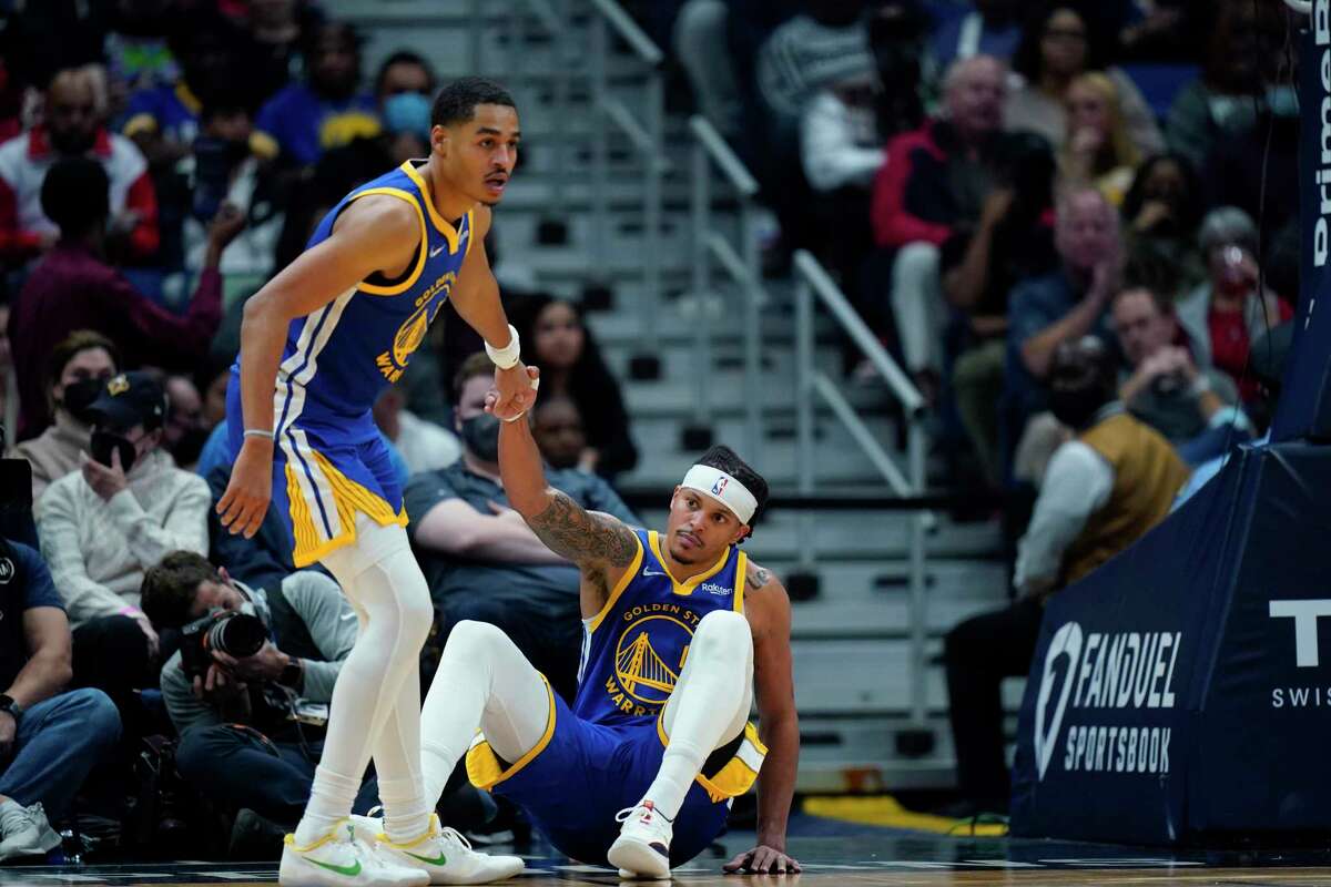 Golden State Warriors guard Jordan Poole helps up guard Damion Lee in the first half of an NBA basketball game against the New Orleans Pelicans in New Orleans, Thursday, Jan. 6, 2022. (AP Photo/Gerald Herbert)