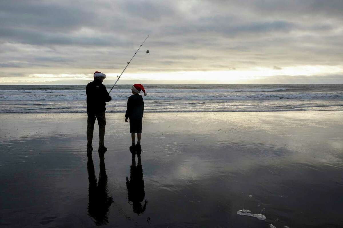 Jamie Sutton teaches his grand nephew Jaxson, 8, how to fish for Dungeness crab while at Stinson Beach, Calif. Light rain and warmer weather were expected across the Bay Area.