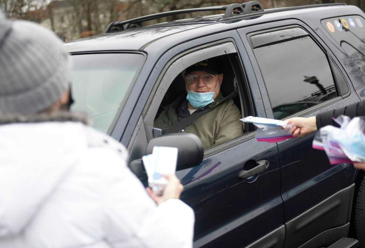 COVID test kits are distributed at Scalzi Park in Stamford, Conn. Sunday, Jan. 2, 2022. 20,000 at-home COVID test kits and masks were distributed to Stamford residents at Scalzi, Kosciuszko and Cummings Parks. Traffic near the distribution locations sat at a standstill for hours as residents queued up early to get in line to receive the test kits.