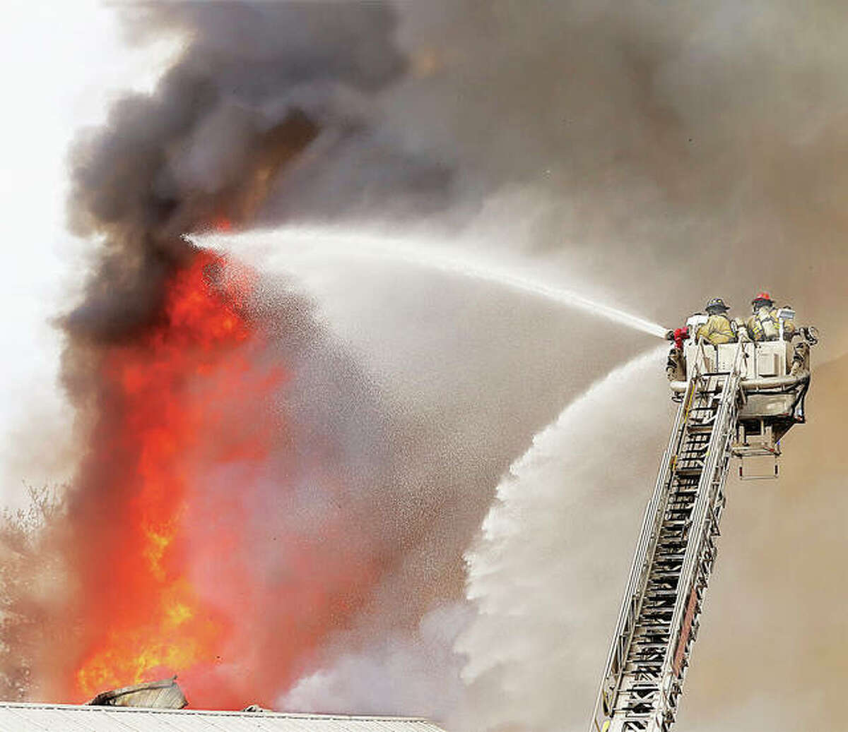 Wood River firefighters pour water on flames shooting 75 feet in the air from Hatch & Kirk on Friday morning.