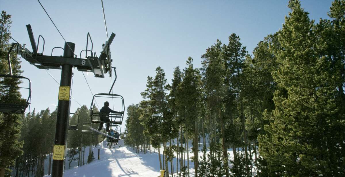 Snowboarders ride a ski lift at Eldora Ski Resort near Boulder, Colorado.