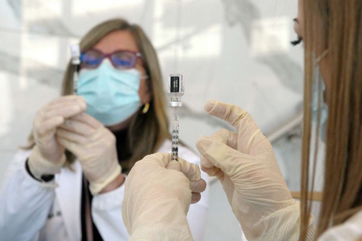 Gina Kelly, right, and Gina Christakos, fill syringes with COVID-19 vaccine at Hartford HealthCare’s new mass vaccination clinic on the west campus of Sacred Heart University, in Fairfield, Conn. March 10, 2021.