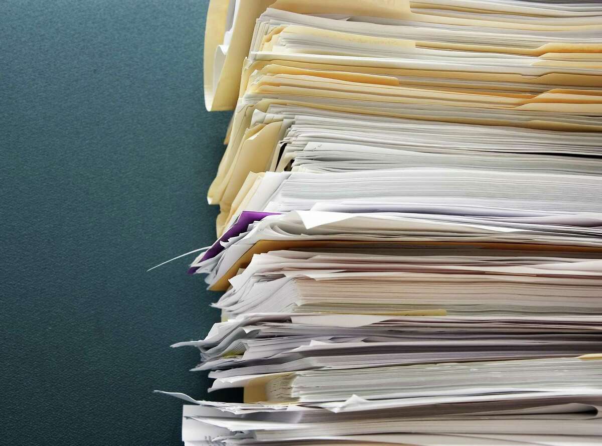 Pile of paperwork against a textured green cubicle wall; STACK OF FILES; STACK OF PAPERS fotolia