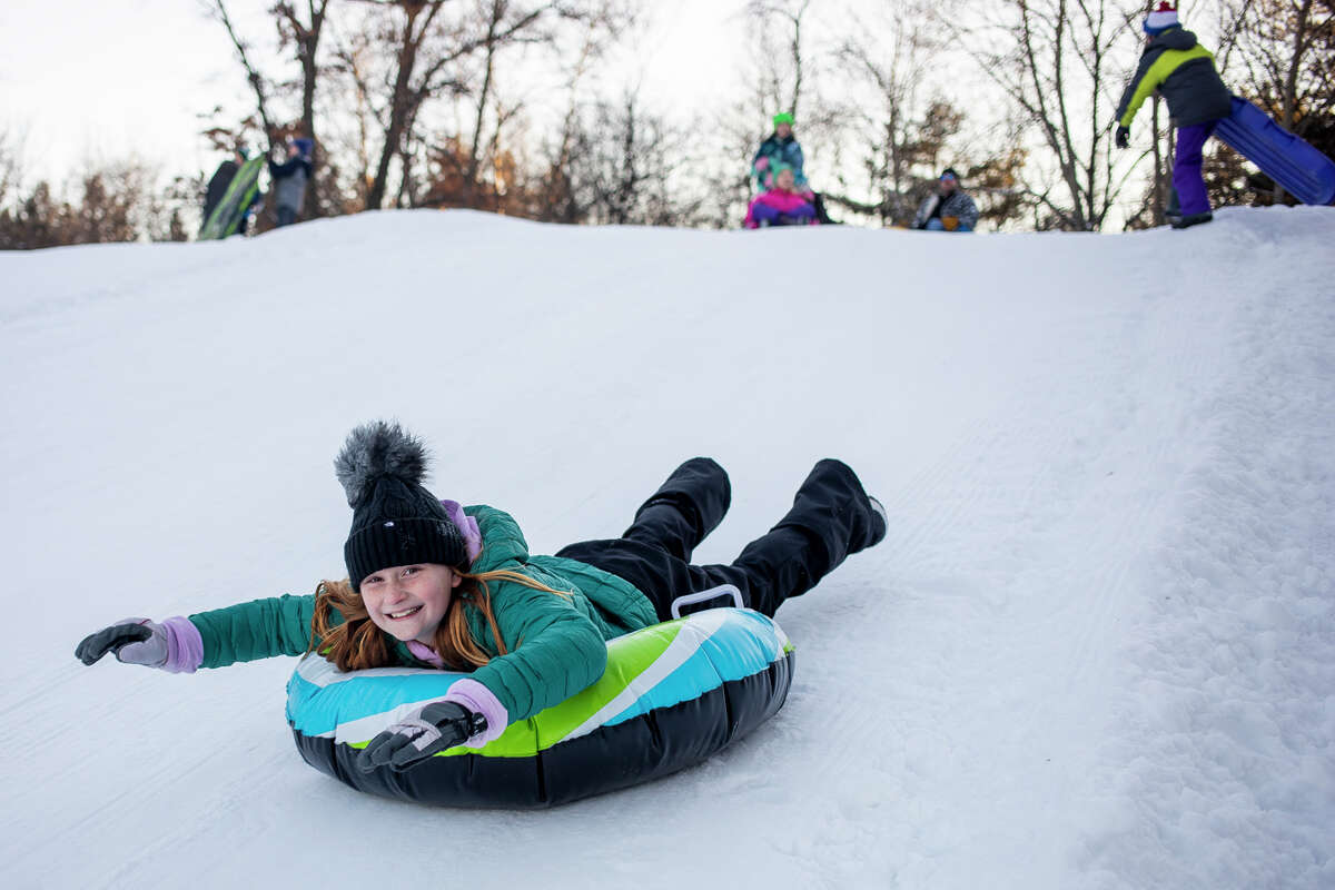 Families speed down the sledding hill at Midland's City Forest