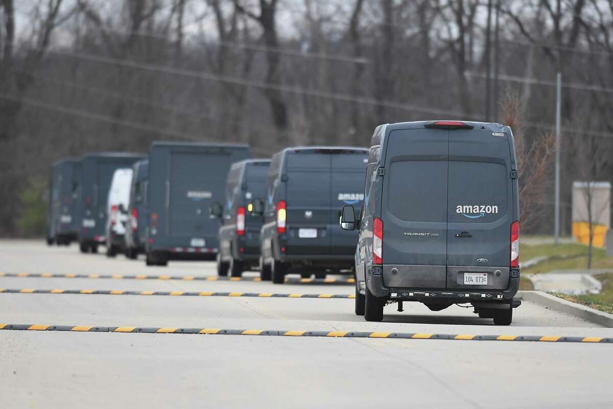 Delivery vehicles sit outside an Amazon distribution center in Edwardsville, Ill. Urban consumers can have almost anything delivered, which erodes opportunities for social interaction.
