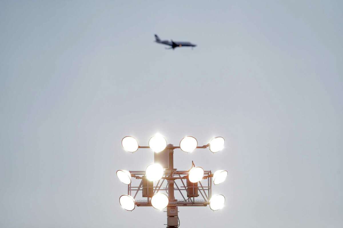 A plane on approach to Norman Y. Mineta San Jose International Airport is seen above a light standard at Excite Ballpark in San Jose. On Friday, two flight attendants on a plane bound for the airport were taken to a hospital upon landing after crew members reported a chemical odor in the rear galley.