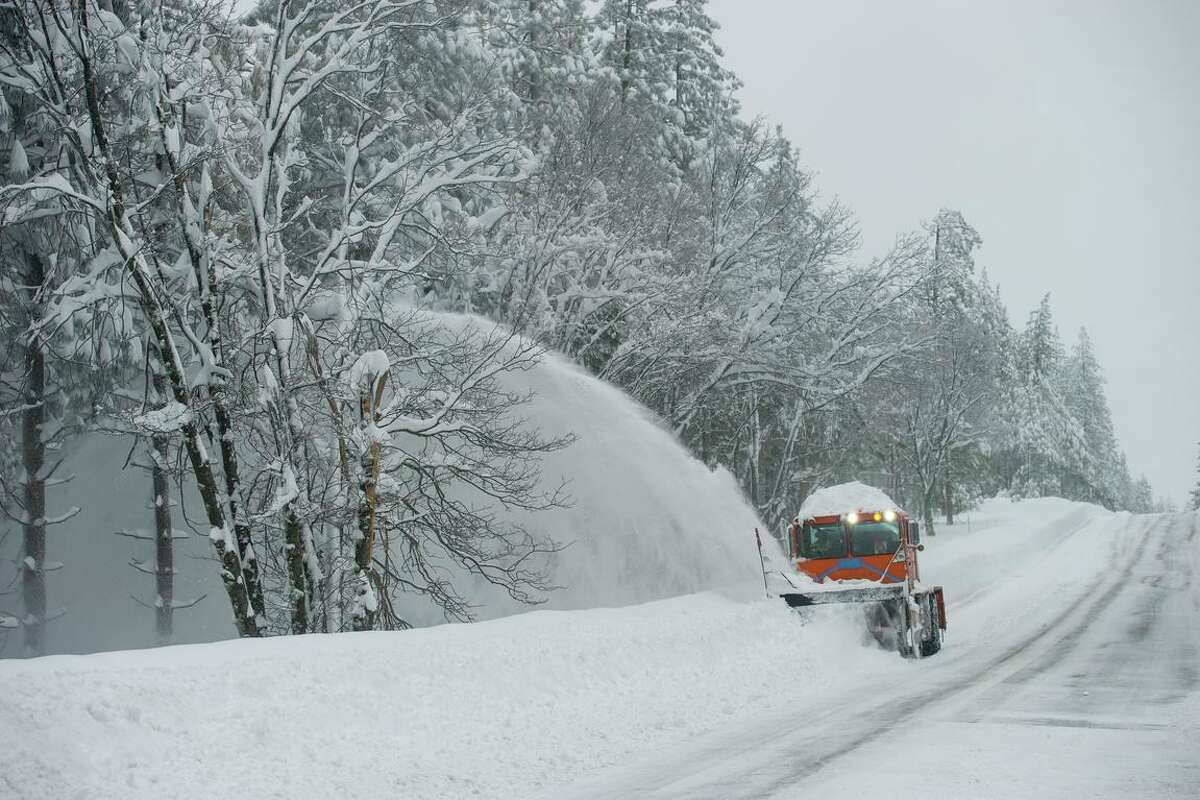 A Caltrans employee clears a section of Highway 20 east of Nevada City in December. The snow from that storm has left thousands in the area without power because of fallen trees and power lines.
