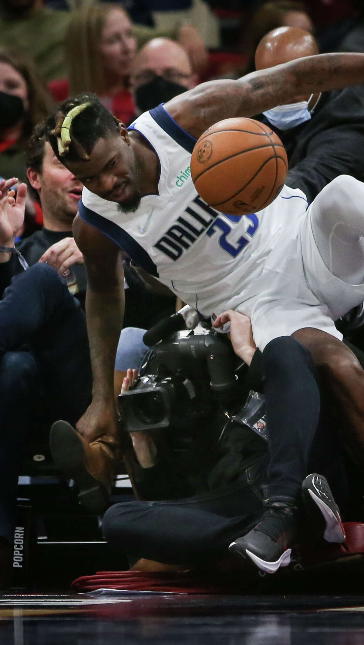 Dallas Mavericks forward Reggie Bullock (25) falls on a television cameraman during the second quarter of an NBA game Friday, Jan. 7, 2022, at the Toyota Center in Houston.