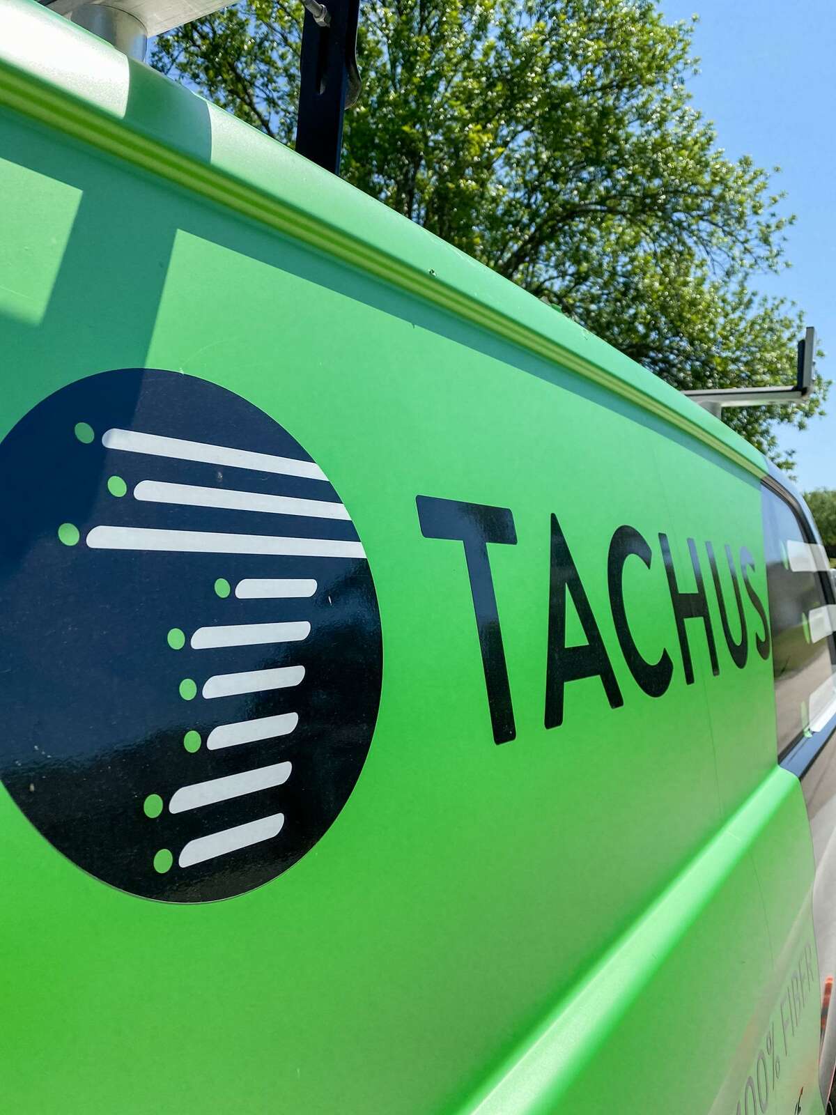 The side of a Tachus van with their logo.