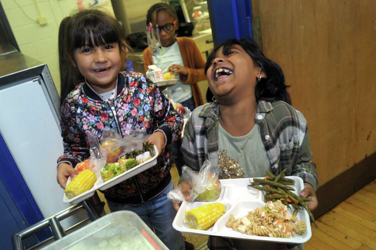 Second grader Samaira Raman, right, shares a laugh with classmate Isabella Sanchez as they exit the food line with their lunches at Jefferson Elementary School, in Norwalk, Conn. Oct. 11, 2019.