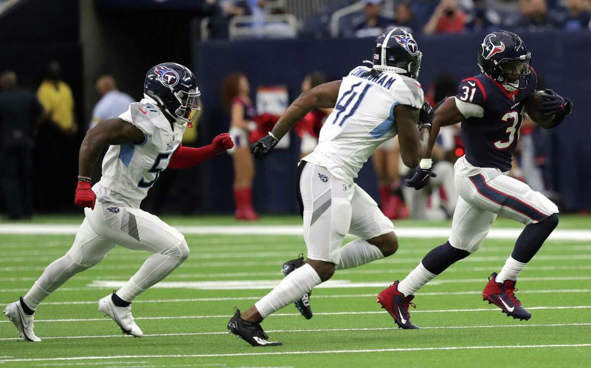 David Johnson #31 of the Houston Texans runs the ball in front of Zach Cunningham #41 and David Long #51 of the Tennessee Titans during the first quarter at NRG Stadium on January 09, 2022 in Houston, Texas.