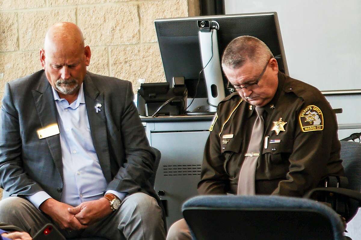 State Sen. Curt VanderWall (left) and Mason County Sheriff Kim Cole participate in a prayer during a Sunday ceremony to honor fallen law enforcement officers who were graduates of West Shore Community College. 