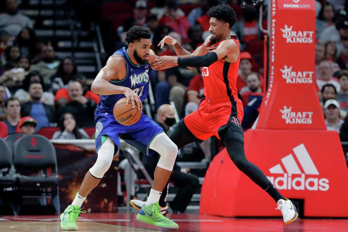 Minnesota Timberwolves center Karl-Anthony Towns, left, pushes off Houston Rockets center Christian Wood, right, as he moves to the basket during the second half of an NBA basketball game Sunday, Jan. 9, 2022, in Houston. (AP Photo/Michael Wyke)