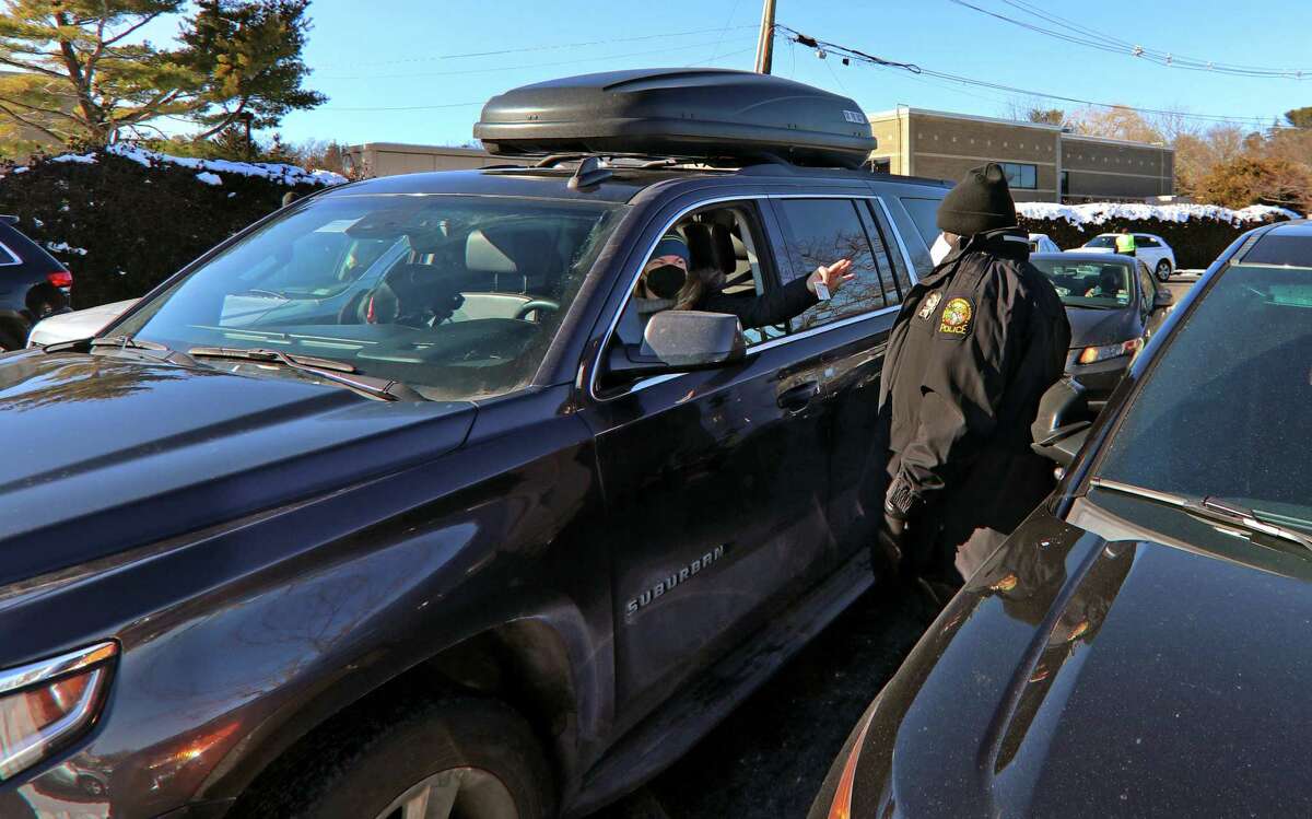 A Greenwich police officer checks a resident's ID at a COVID-19 test kit distribution event at Grass Island Park in Greenwich, Conn., on Saturday Jan. 8, 2021.