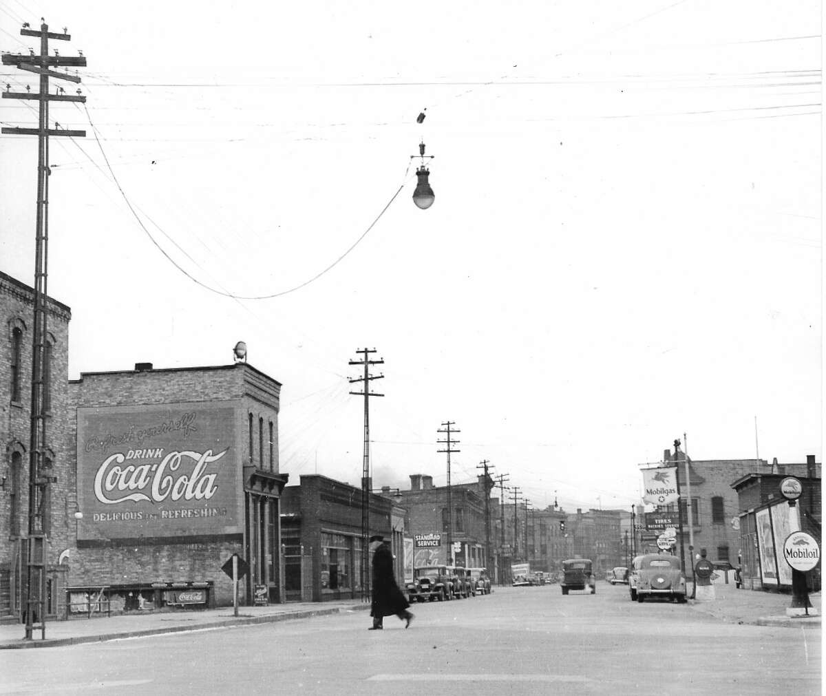 This photo shows a view looking west on River Street near the corner of Smith and River Street around the late 1930s. The building with the Coca-Cola billboard attached is 289 River St.