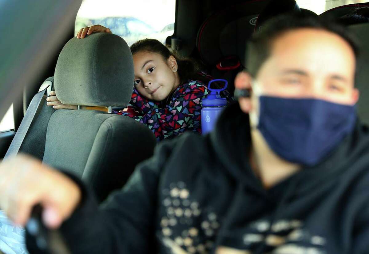 Bowman Elementary School student Amilya Middaugh-Lugo, 7, watches from the back seat as her mother, Angelina Lugo, waits in the long line of cars to pick up a Chromebook at Hayward Unified headquarters.