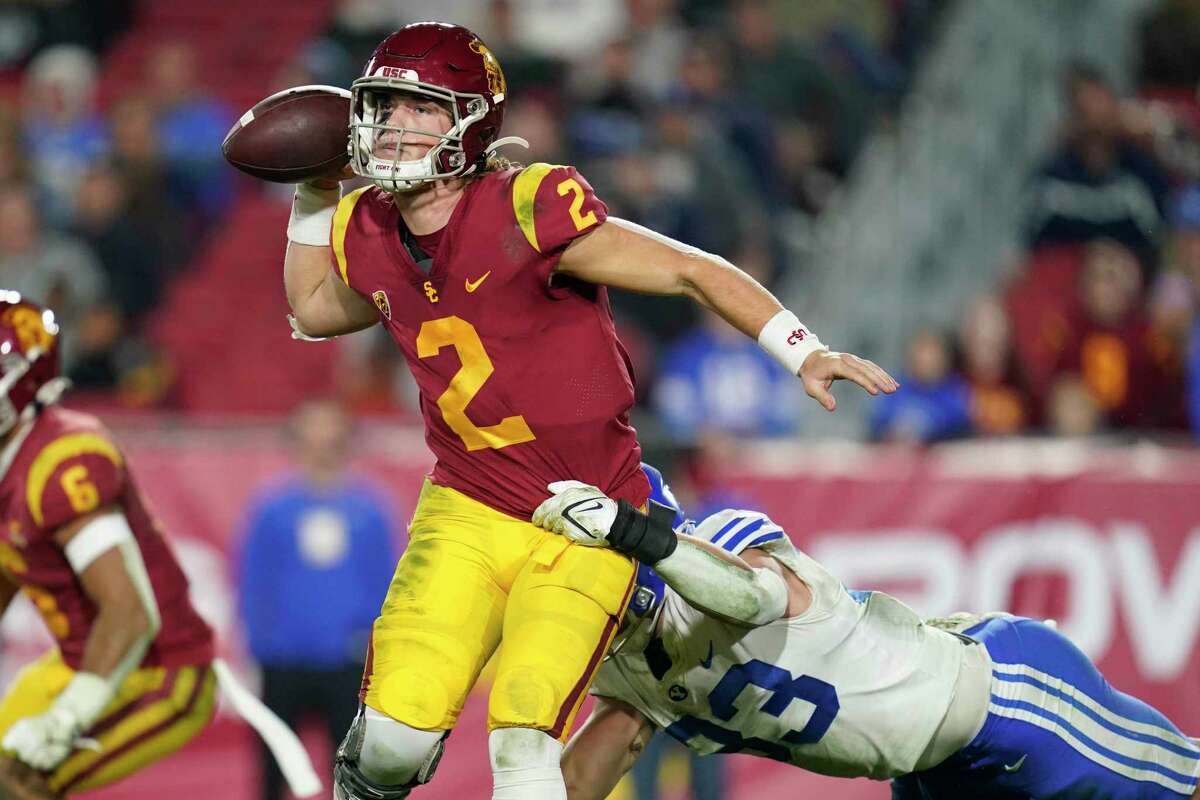 FILE - Southern California quarterback Jaxson Dart (2) throws a pass while being tackled by BYU linebacker Ben Bywater (33) during the second half of an NCAA college football game in Los Angeles, Saturday, Nov. 27, 2021. The Trojans would need a big turnaround in 2022 to propel Dart into the Heisman conversation. (AP Photo/Ashley Landis, File)