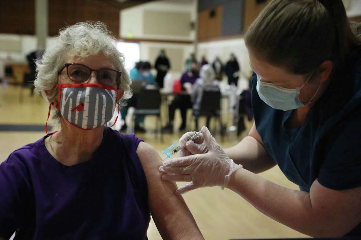 Marna McKenzie (left) of Sebastopol gets a COVID-19 shot at a vaccination clinic for older adults in Rohnert Park. Rohnert Park is in Sonoma County, where health officials issued a ban on large gatherings — more than 50 people convening inside, or more than 100 people outside.