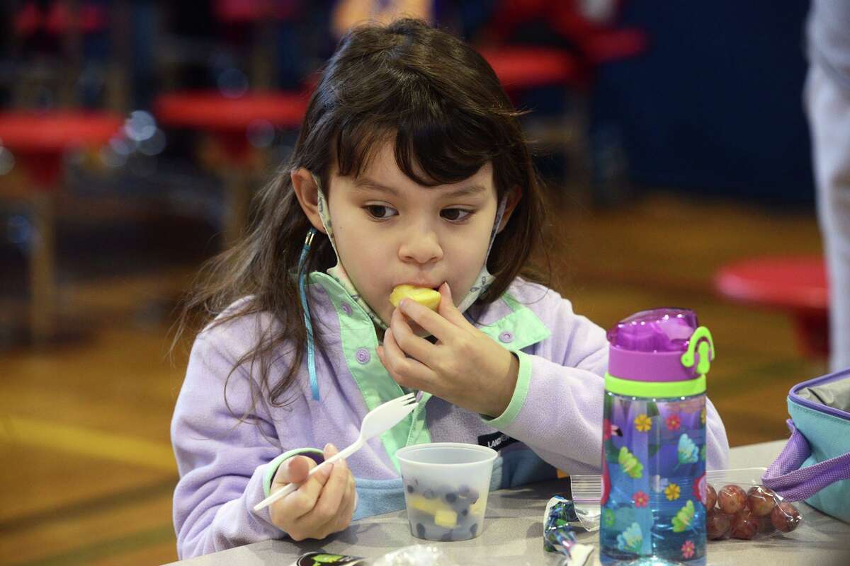 First-grader Ciara Coronato samples a piece of pineapple from her Mood Boost “smart fruit salad” during lunch at Cranbury Elementary School, in Norwalk, Conn. Jan. 11, 2022.