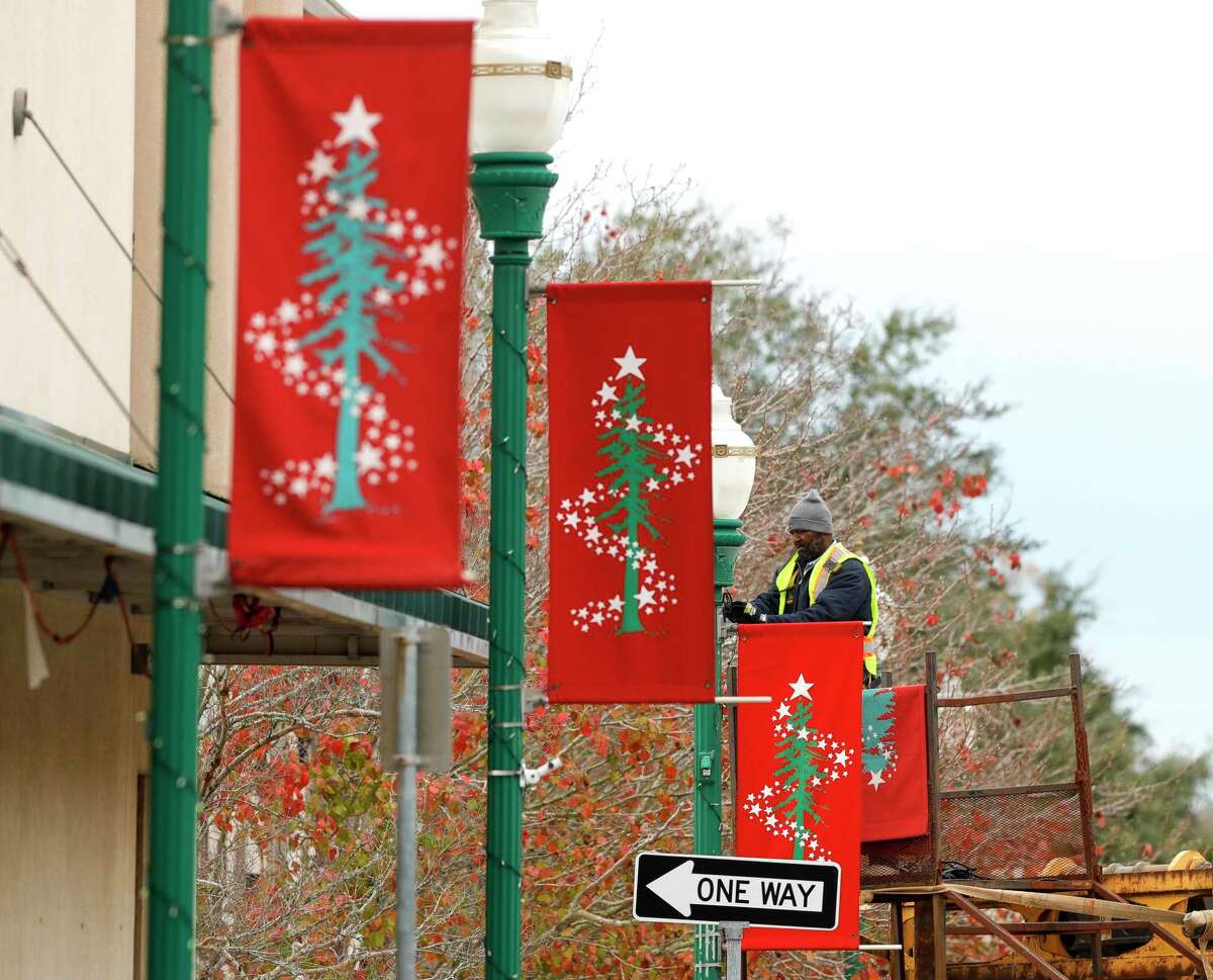 Leotis Warren uninstalls a holiday banner from light pole as employees with Conroe's Park and Recreation Department take down the Conroe’s downtown holiday decorations, Tuesday, Jan. 11, 2022. While it takes two weeks for the department to transform the downtown streets for the festive season with various light displays, banners and Christmas trees, it takes about a week to disassemble and store.