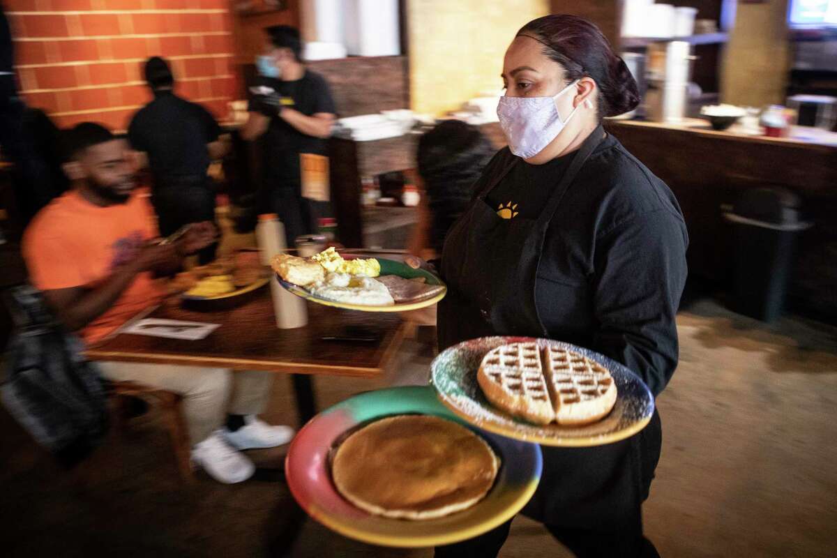 Karina Cabello brings out plates of food to customers at The Breakfast Klub Friday, Jan. 7, 2022 in Houston. As omicron continues to spread at unprecedented rates, Houston-area businesses are feeling the pinch of staff shortages and bracing for the worst. Owner Melvinie Davis said the business has relied on out-of-state clientele to keep her businesses running strong after two years of closures and uncertainty. Now, she fears another lockdown could upend that stability.