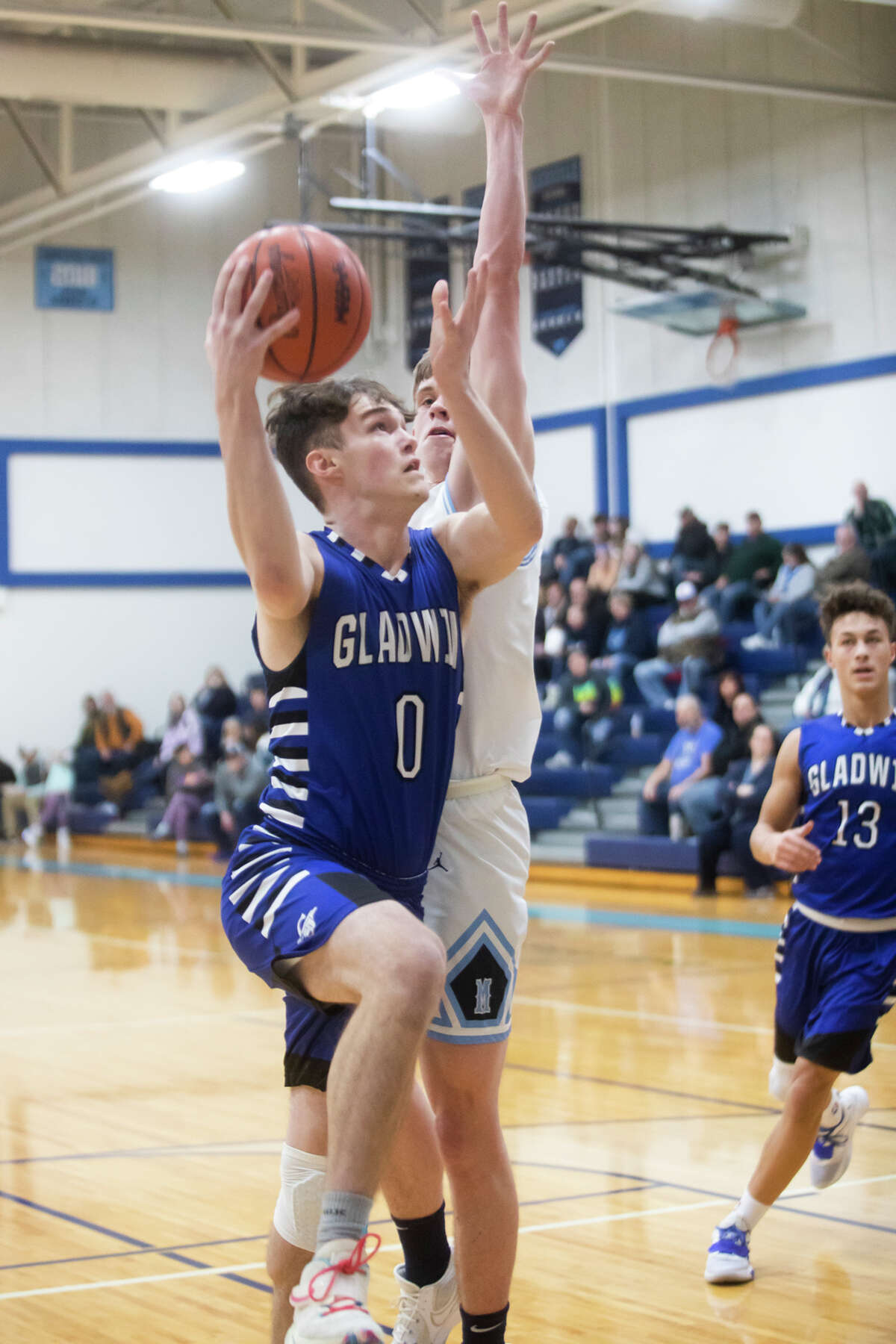 Gladwin's Denver Peters takes a shot while Meridian's Sawyer Moloy guards him during their game Tuesday, Jan. 11, 2022 at Meridian Early College High School.