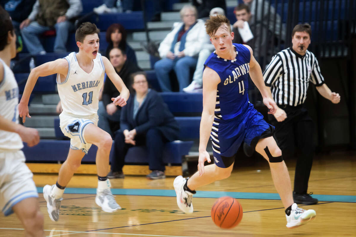 Gladwin's Lucas Mead dribbles down the court while Meridian's Nick Metzger follows behind during their game Tuesday, Jan. 11, 2022 at Meridian Early College High School.